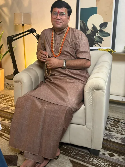 Rudra Sharan Mishra seated in an armchair, holding a japa mala