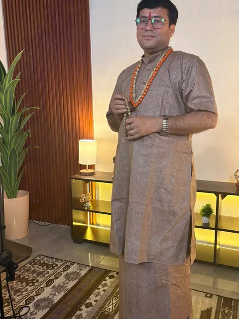Rudra Sharan Mishra standing in a kurta and dhoti, wearing prayer malas